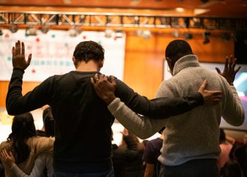 two men holding ear others hand